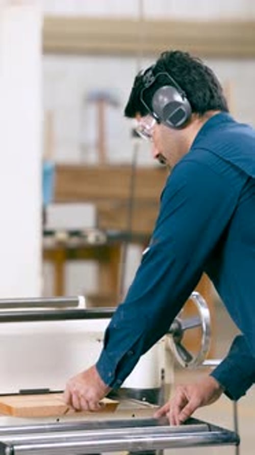 Carpenter Using a Thickness Planer Machine in His Workshop Vertical