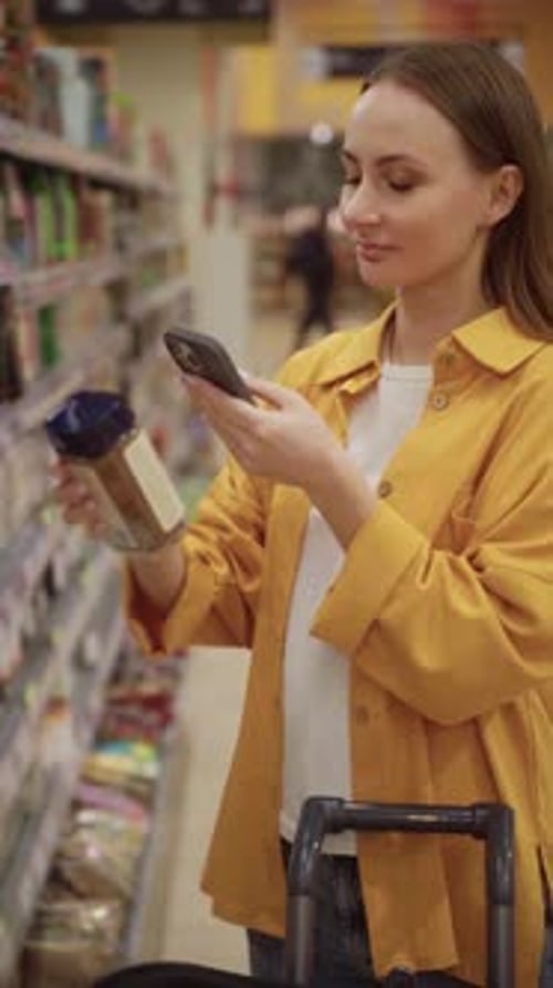 Woman Scans Coffee Can in Supermarket Aisle While Shopping for Groceries