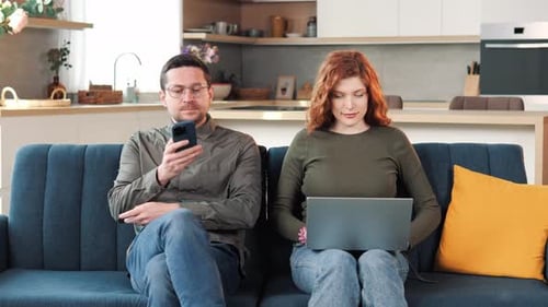 Couple Relaxing on Couch Using Technology