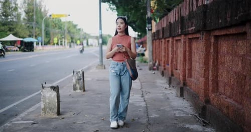 Woman Walking on Sidewalk Holding Smartphone