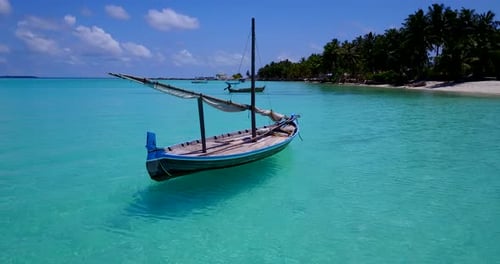 close up low altitude aerial view of a small sailboat floating on the shallow turquoise waters of th