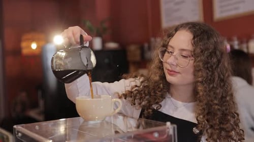Young Female Barista Pouring Steaming Coffee