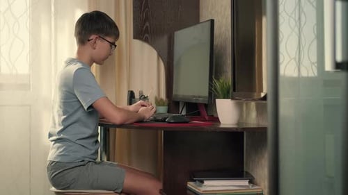 Boy Writes Program Code at Home Using Computer