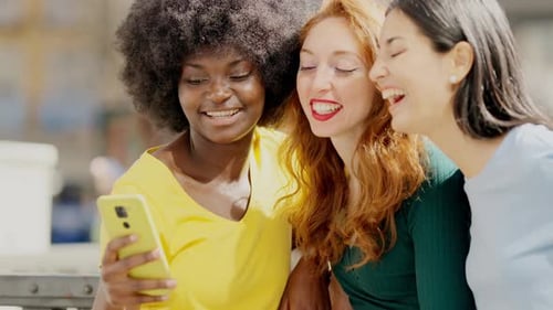 Friends Enjoying Smartphone Content Together Outdoors