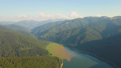 Aerial View of Big Lake with Clear Blue Water Between High Mountain Hills Covered with Dense