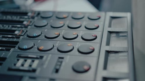 Hand Adjusting Dials on a Mixing Board