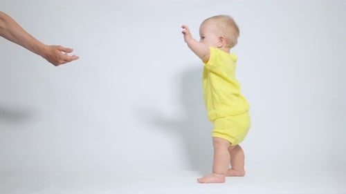 Baby Taking First Steps Towards Parent's Hand