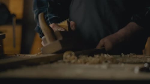 Woodworker Shaping Plank with Hand Plane in Workshop