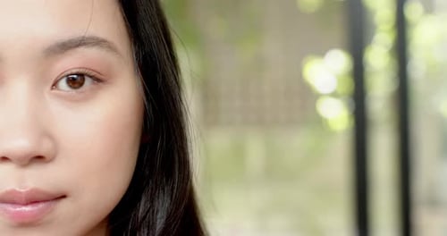 Smiling woman with long hair showing dimples, close-up portrait outdoors, copy space