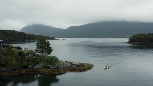Aerial drone shot of kayakers on huge lake with mountains in the background