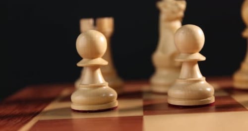 Schachfiguren auf Spielbrett vor schwarzem Hintergrund, Nahaufnahme. Kamera bewegt sich nach rechts