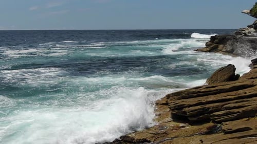 Drone flying over wet rocks from ocean waves, Bondi Beach in Australia. Aerial forward low altitude