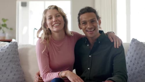 Smiling Couple Waving from the Couch at Home