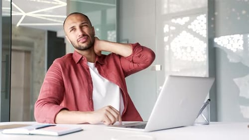 Man Massaging Stiff Neck at Office Desk