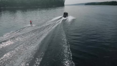 A Young Man Rides a Wakeboard A Sports Guy Rides on the Water on a Board Behind a Boat Top View From