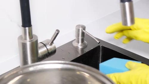 Concepto de lavado de platos: una mujer presiona detergente sobre una esponja de cerca