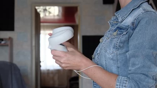 Woman Inspecting White Virtual Reality Controllers Indoors