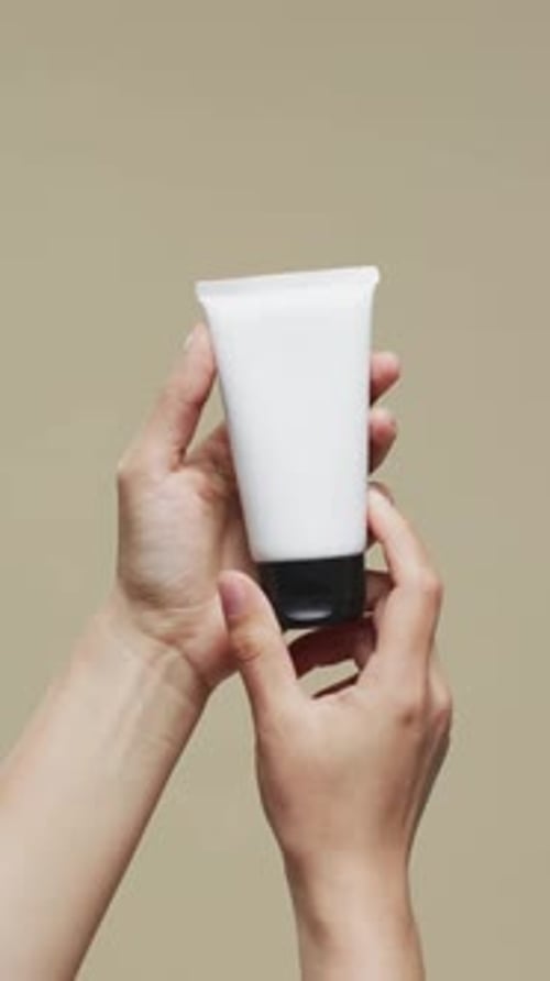 Hands Holding White Cosmetic Tube for Beauty Presentation