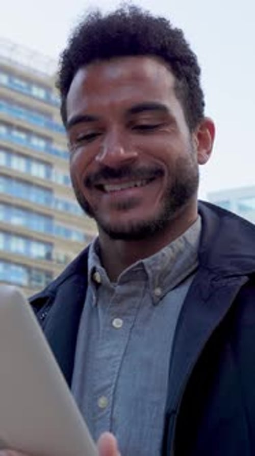 Young Adult Latin American Businessman Using Tablet in Modern City Area
