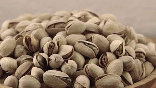 Pile of pistachios in wooden bowl, close up