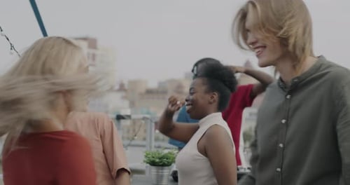 Slow Motion of Carefree Couple Dancing on Rooftop with Friends Laughing Enjoying Party Together