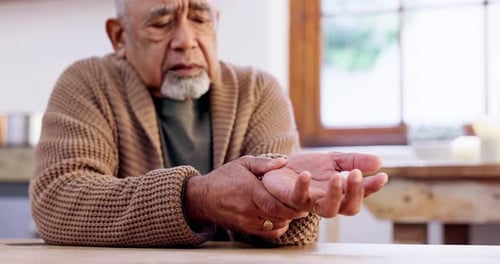Senior Adult Massaging Sore Wrist at Table