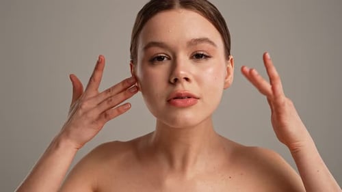 Young Woman Posing at Camera Playfully Smiling Touching Smooth Skin Close Shot Isolated on White