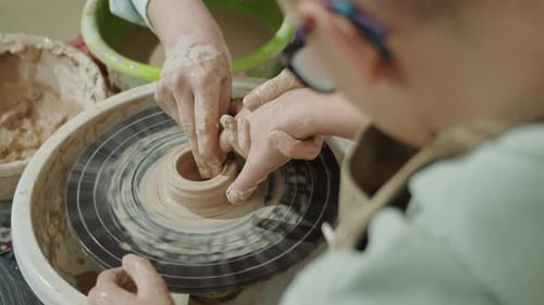 Child Learning to Mold Clay Pot on Wheel