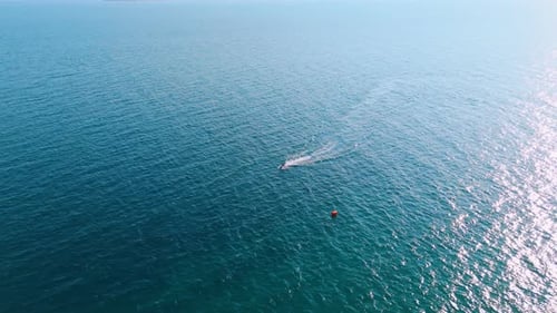 Der einsame Jet-Ski-Scooter bewegt sich schnell an der sonnengeblendeten Wasserlandschaft in der Nähe der roten Boje vorbei.