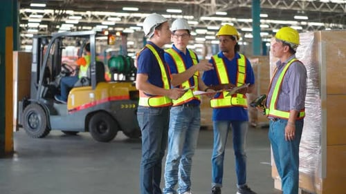 Warehouse manager discuss together during walk in workplace with other workers