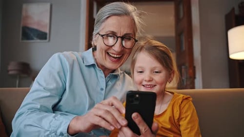 Grandmother and Granddaughter Enjoying Smartphone Together Indoors