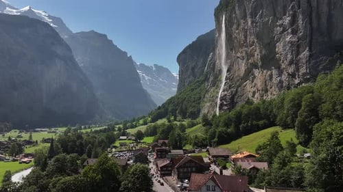 Drone pushes forward over charming houses with street view, surrounded by lush trees and landscape n