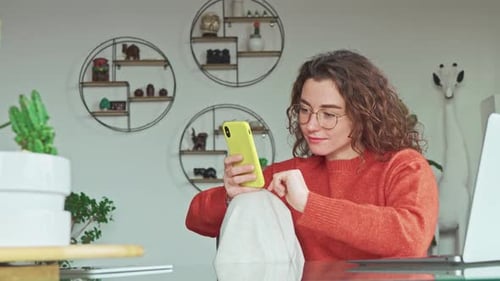 Happy Young Woman Sitting at Home Using Social Media Apps on Mobile Phone
