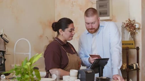 Manager Discussing Work with Waitress at Cafe Counter