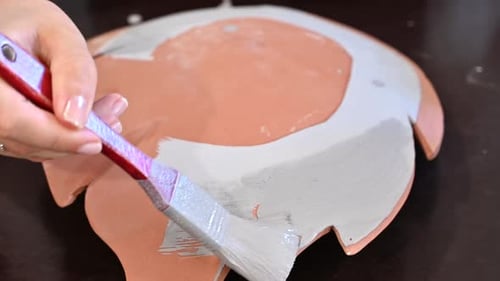 Woman painting a flower vase at pottery workshop