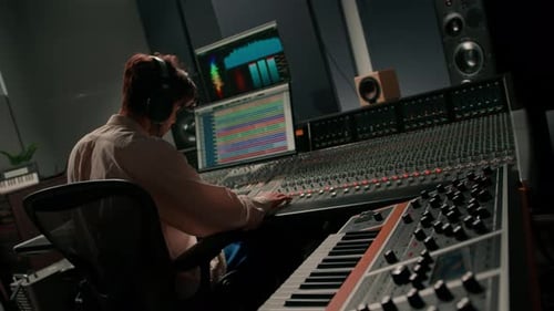 Energetic audio engineer producer working in recording studio mixing tracks on console and hit maker