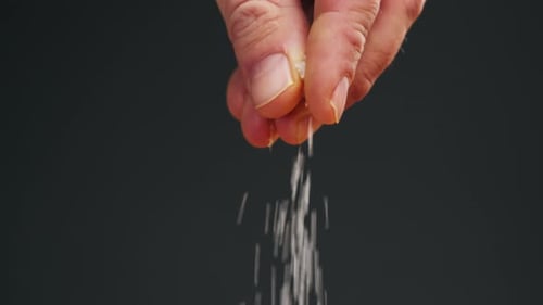 White Salt Closeup Macro Spice for Food Sea Salt for Bath Man Hand Srewing Salt on Table