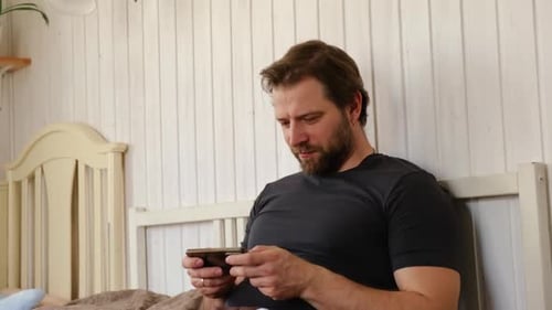 Man Relaxing in Bed Watching Content on Phone