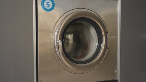 Laundry Machine Labelled 5 with Clothes Spinning Inside During Wash Cycle