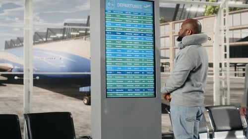 Checking Departure Board Timetable Data and Man in Airport Lounge