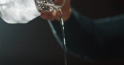 Close up of a professional bartender is preparing an alcoholic cocktail with ice cubes to customer
