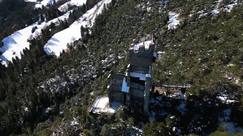an old ruin of a castle on a rock in the mountains in winter