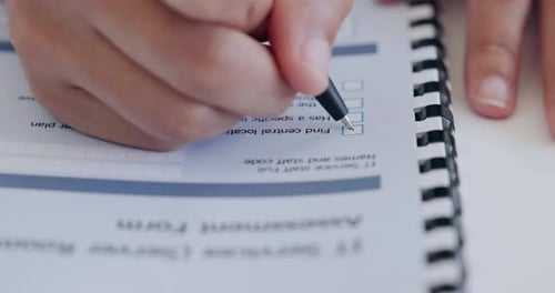Hand Filling Out Assessment Form with a Pen