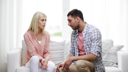 Adult man and woman talking on sofa at home