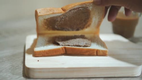 Hand Spreading Peanut Butter on Slice of Bread