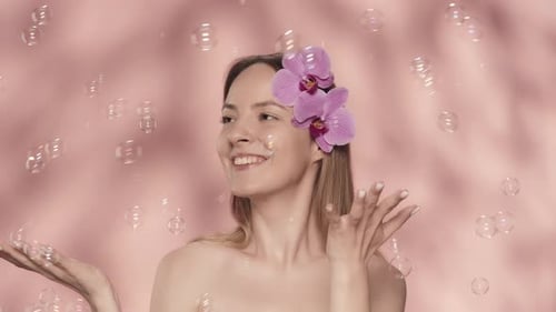 Tender Beautiful Woman with Naked Shoulders in the Studio on a Pink Background A Woman with Orchid