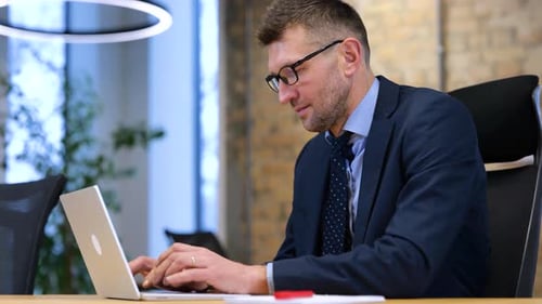 Echtzeit-Video: Kaukasischer Mann arbeitet im modernen Büro an einem hellen Holztisch. Mann sitzt
