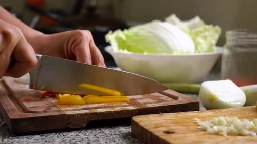Hands Cutting Yellow Bell Pepper Into Strips In The Kitchen. close up
