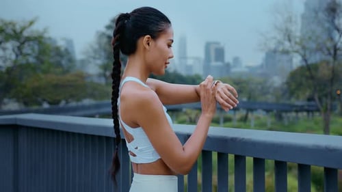 Athletic Woman Checking Smartwatch in Urban Park