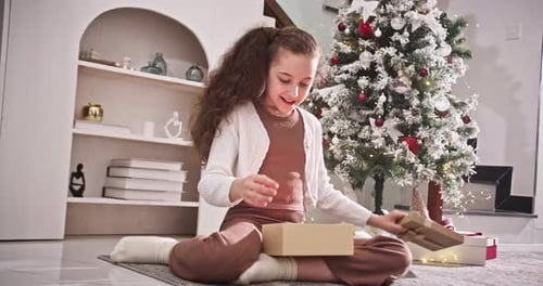 Excited Girl Opening a Christmas Gift at Home